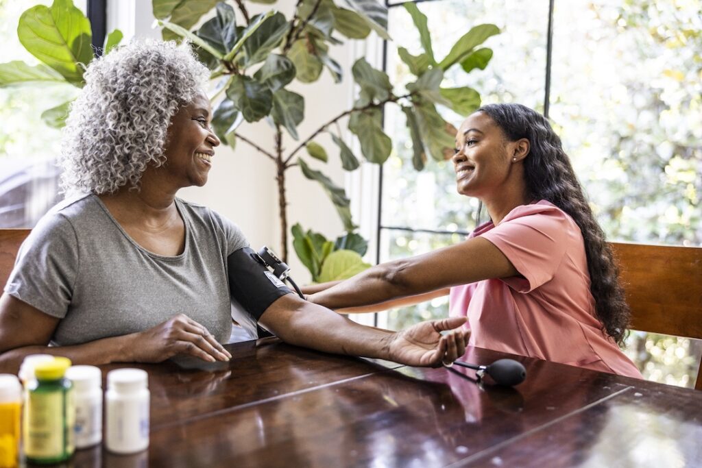 in home healthcare provider measuring senior woman's blood pressure in her home